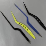 Four curved precision tweezers on gray surface