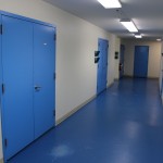 A hallway with two blue doors and white walls.